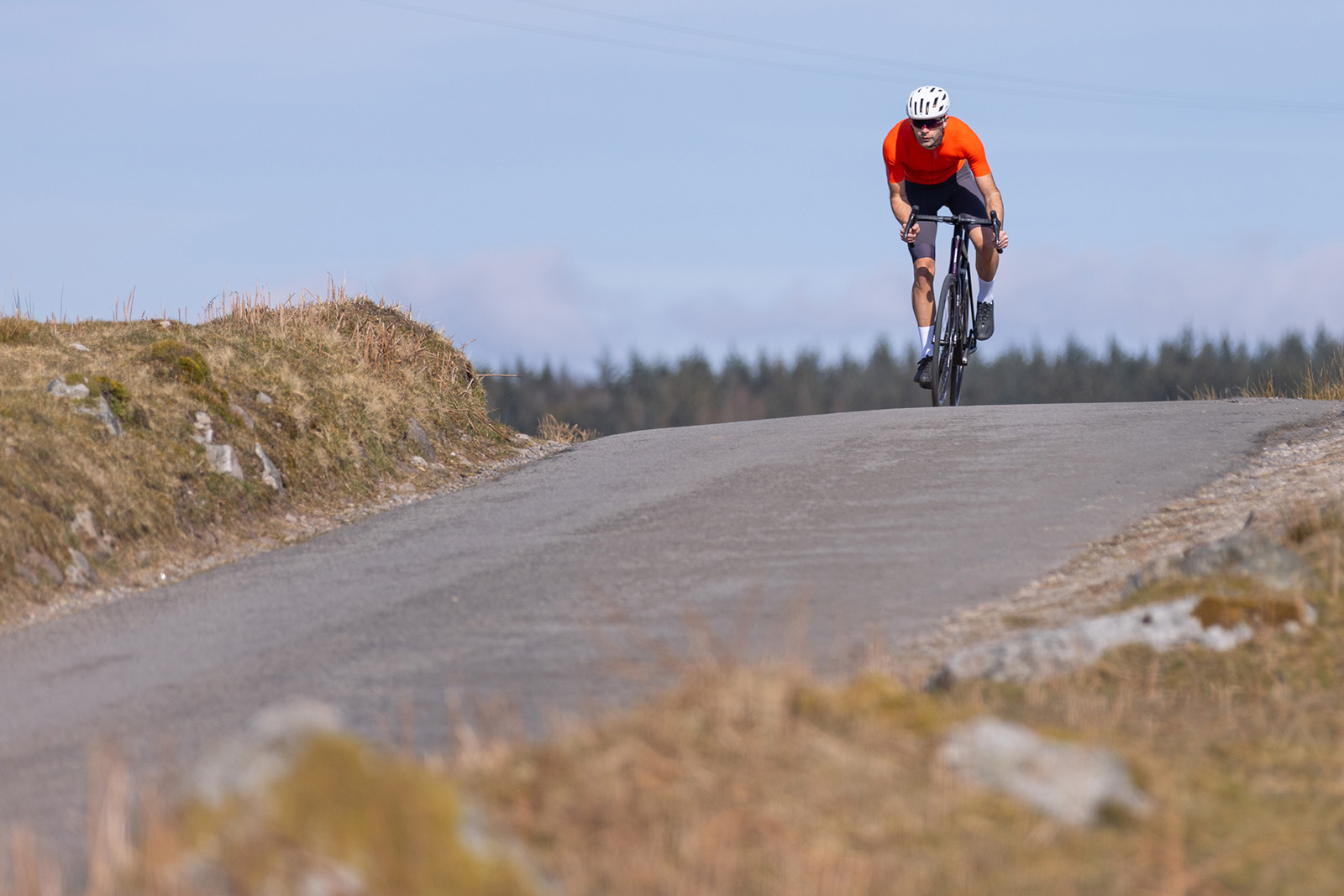 Male cyyclist in orange top riding the Orbea Orca M20i Team road bike