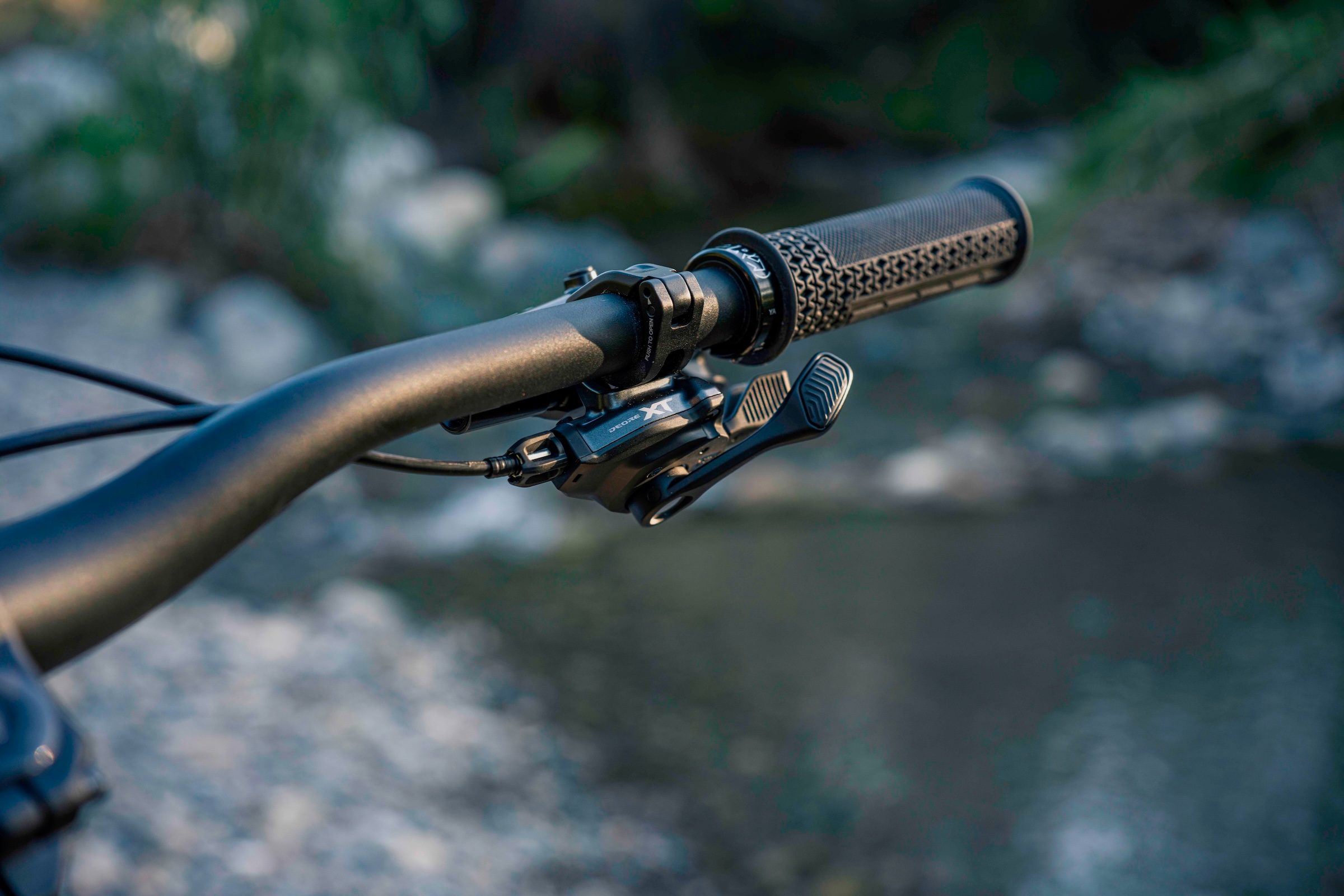 Close-up of a Shimano Deore XT M8200 mechanical shifter mounted to a mountain bike handlebar.