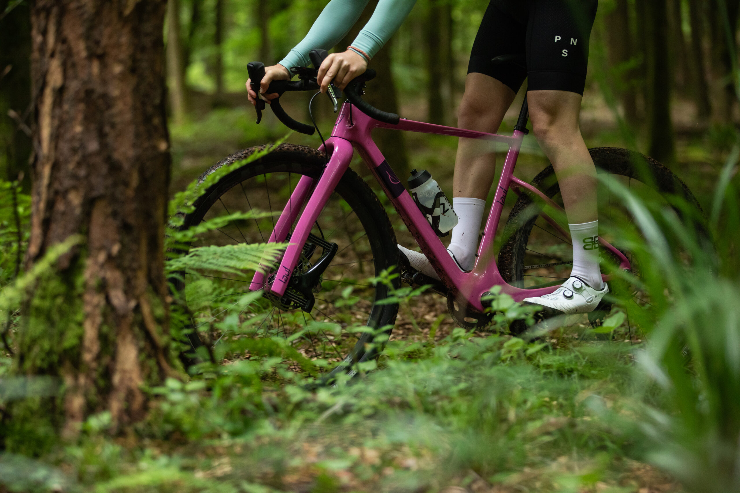 Liam Cahill coasting on pink Lauf gravel bike through woods
