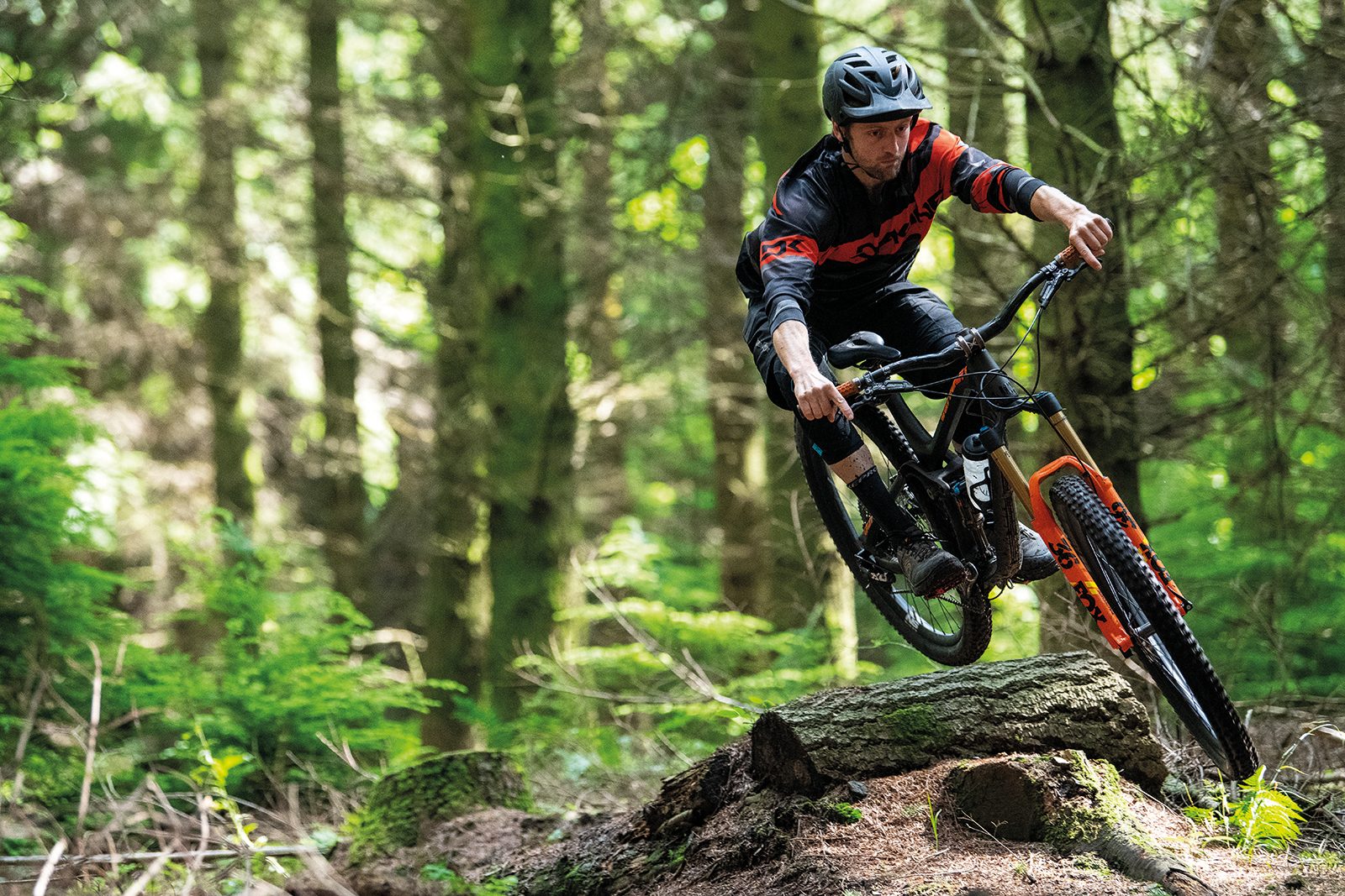 male cyclist riding full suspension mountain bike in woods